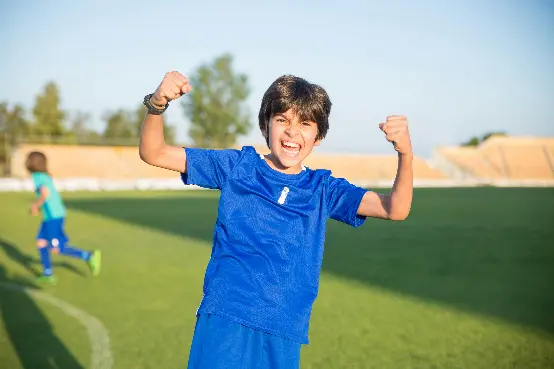 Child celebrating by raising arms and shouting.